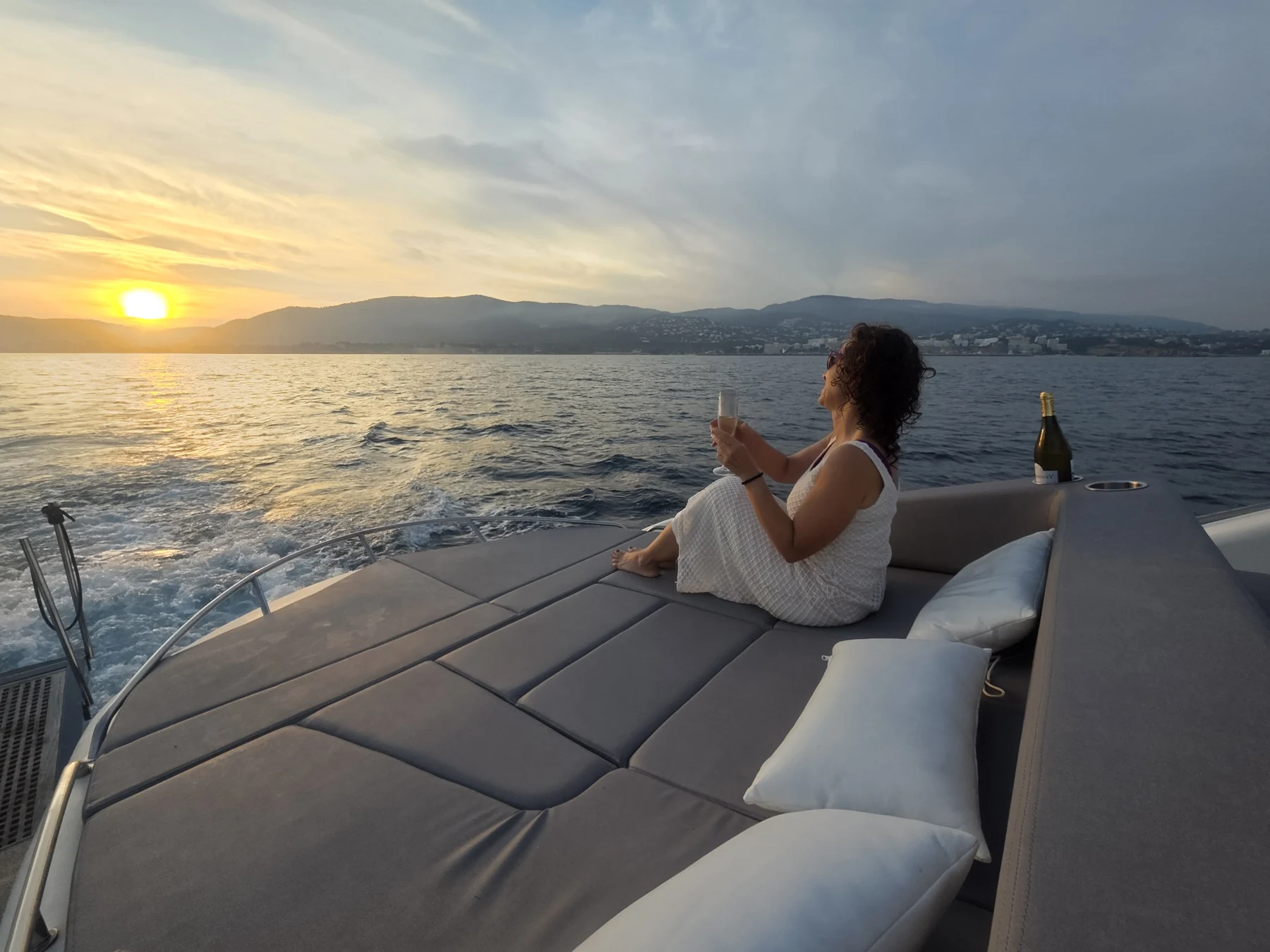 Una mujer disfruta de una copa mientras contempla el atardecer desde cubierta