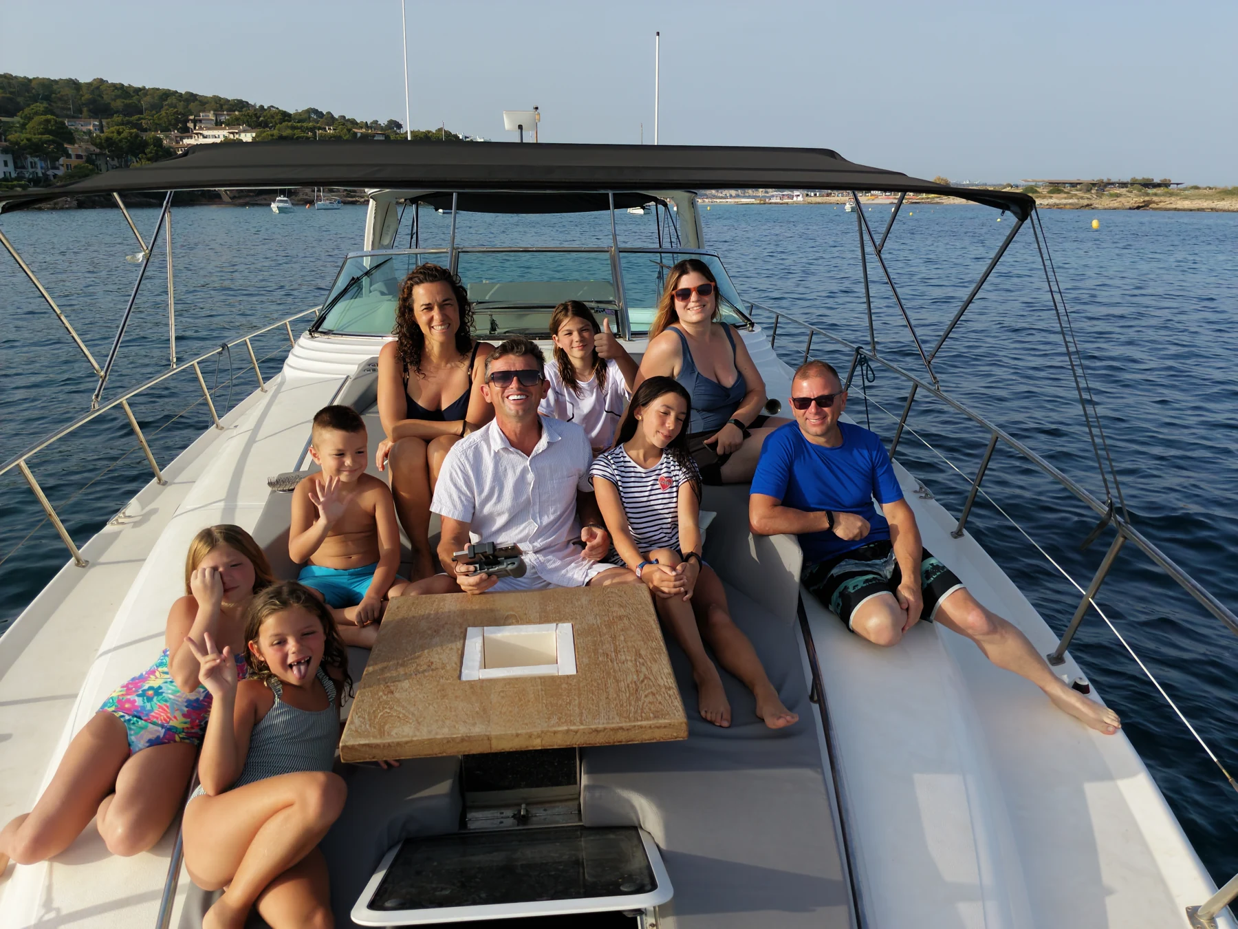 Un grupo de adultos y niños sonríe y saluda a la cámara a bordo